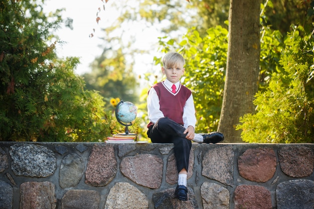 Adorable écolier avec livres et globe à l&#39;extérieur.