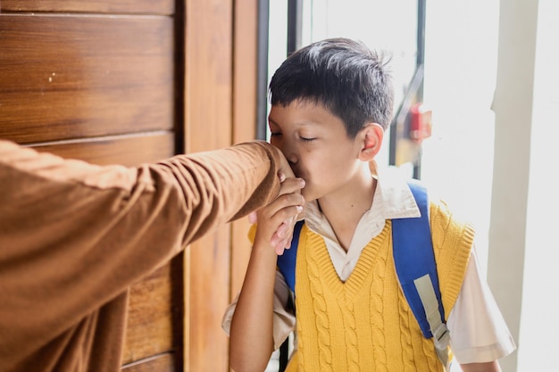 Adorable écolier portant l'uniforme baiser les mains de la mère allant à l'école, concept de retour à l'école.