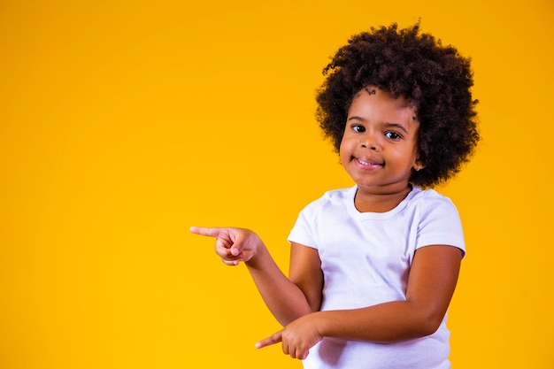 Adorable enfant afro pointant vers un espace libre pour le texte