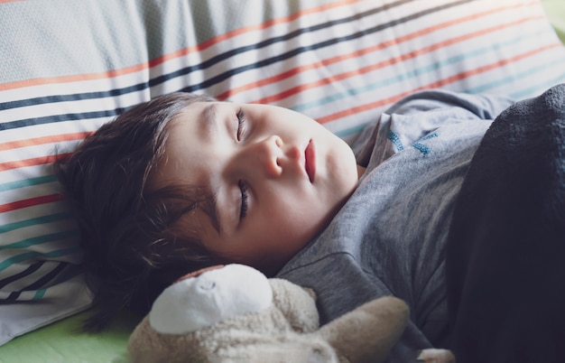 Adorable enfant endormi dans son lit, endormi petit garçon mignon dans son lit, beau garçon endormi