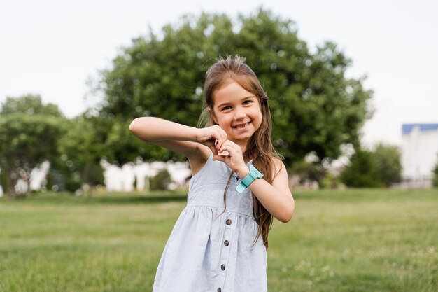 Adorable enfant fille montrant le cœur avec ses mains Un tout-petit mignon montre la paix et l'amour