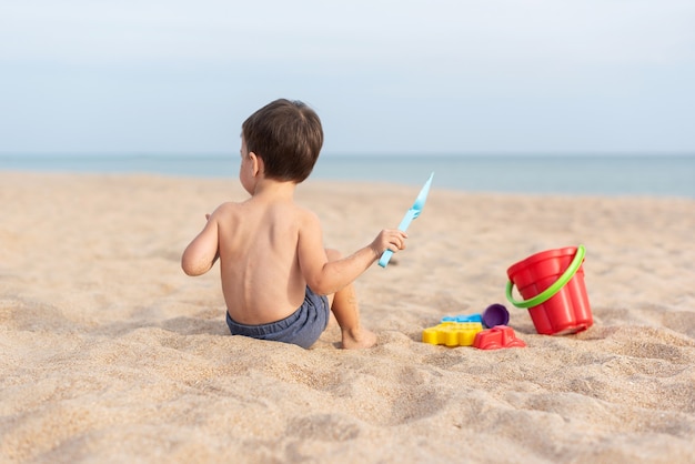 Adorable enfant joue au bord de la mer dans le sable avec des jouets Vacances d'été