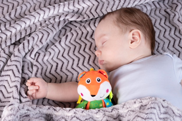Adorable enfant, avec un jouet préféré, dort détendu et s'étale sur le lit des parents