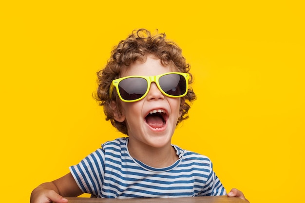 Adorable enfant à lunettes de soleil lumineuses sur orange