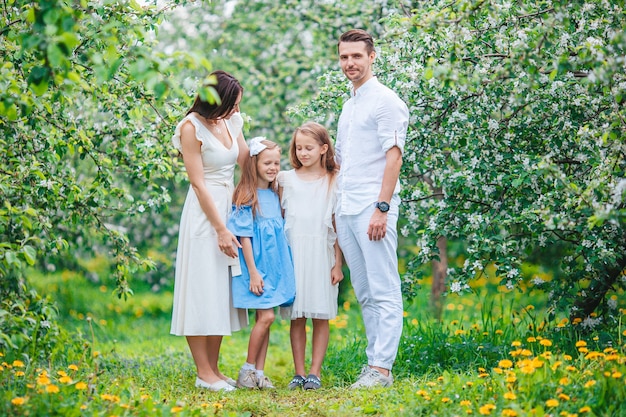 Adorable famille dans un jardin de cerisiers en fleurs sur une belle journée de printemps