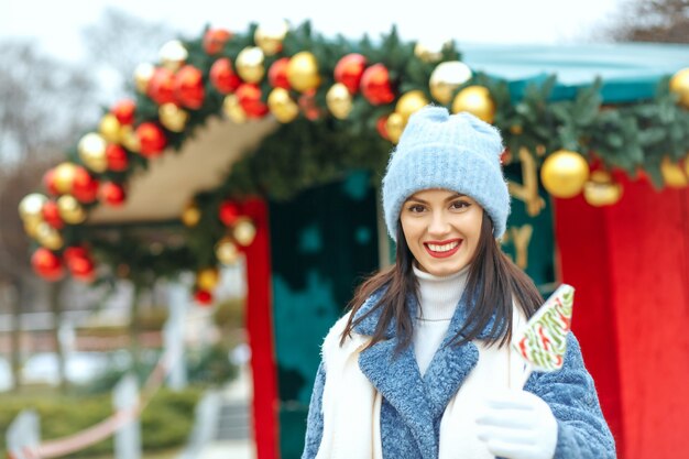 Adorable femme souriante tenant des bonbons au marché de Noël. Espace d'emprit