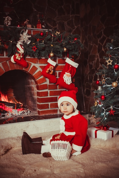 Adorable fille assise près de la cheminée et jouer avec des cônes - Décorations de Noël