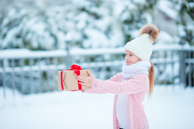 Adorable fille avec cadeau de boîte de Noël en hiver en plein air à la veille de Noël