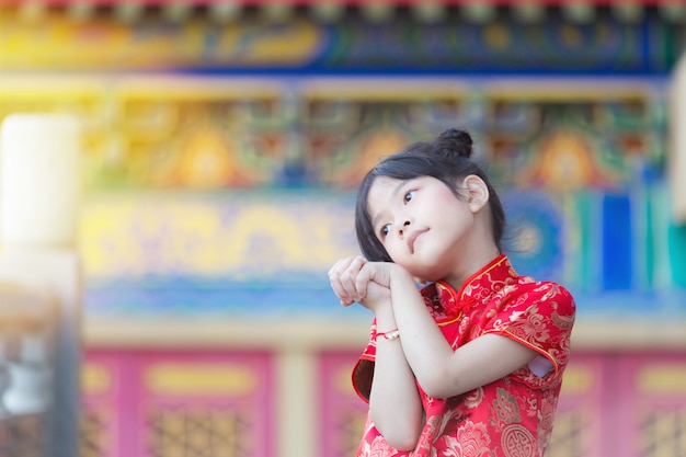 Photo adorable fille chinoise heureuse rêvant d'un cadeau d'enveloppe de ses parents pour le nouvel an chinois