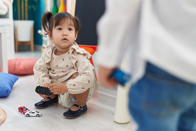 Adorable fille chinoise jouant avec des jouets de voitures à la maternelle