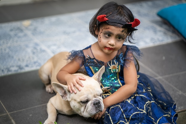 Adorable fille en costume d'halloween assise en plein air avec son chien