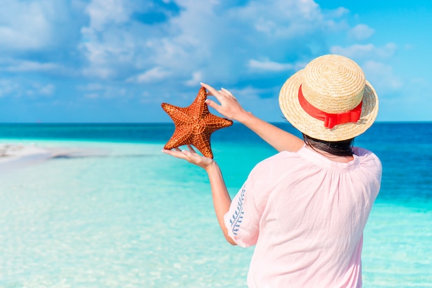 Adorable fille avec des étoiles de mer sur la plage