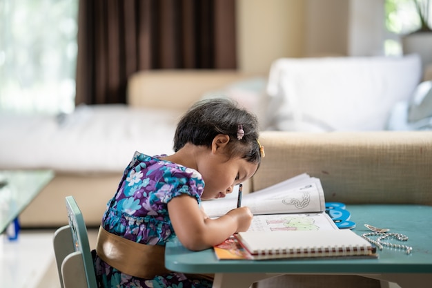 Adorable fille à faire ses devoirs à table à l'intérieur