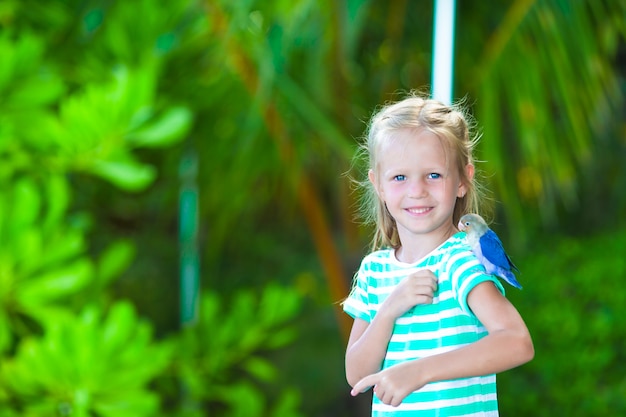 Adorable fille heureuse à la plage avec petit oiseau coloré