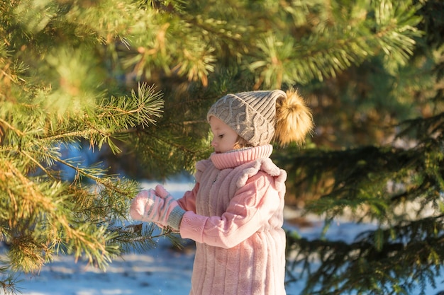 Adorable fille joue avec le pin dans la forêt d'hiver