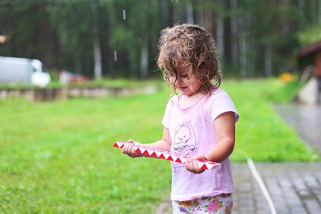 Adorable fille marchant avec un jouet à l'extérieur le jour de pluie