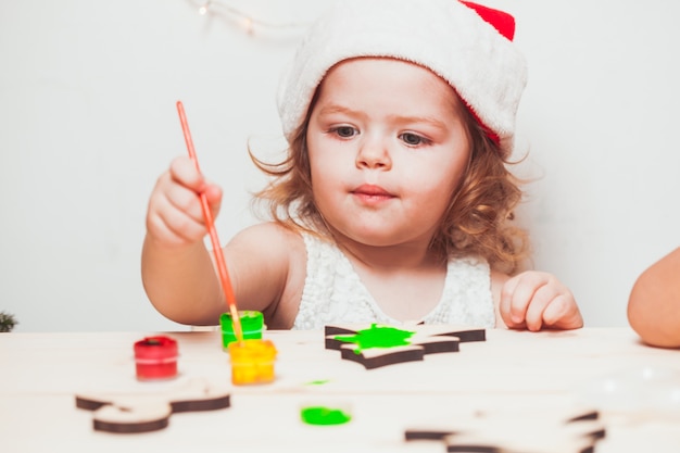 Adorable fille peint des figurines de Noël en bois