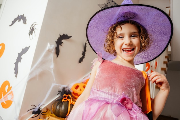 Adorable fille posant en robe rose et chapeau de sorcière