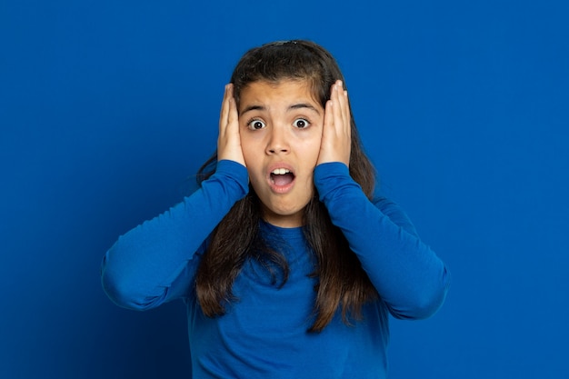 Adorable fille préadolescente avec maillot bleu gesticulant sur mur bleu