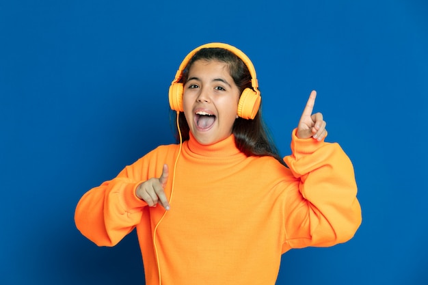 Adorable fille préadolescente avec maillot jaune gesticulant sur mur bleu