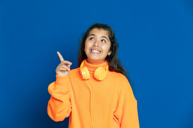 Adorable fille préadolescente avec maillot jaune gesticulant sur mur bleu