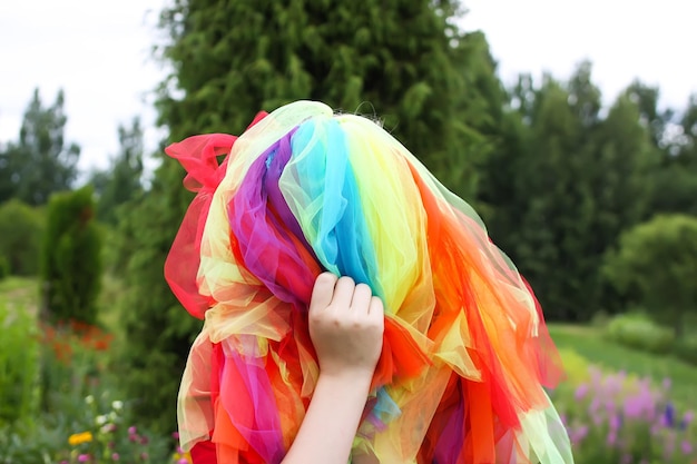 Adorable fille en robe arc-en-ciel colorée sur la tête jouant à l'extérieur