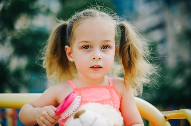 Adorable fille en robe swing sur aire de jeux dans le parc. Petite fille en robe sur l'aire de jeux en été