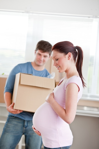 adorable future mère avec mari debout dans leur nouvelle maison déballage