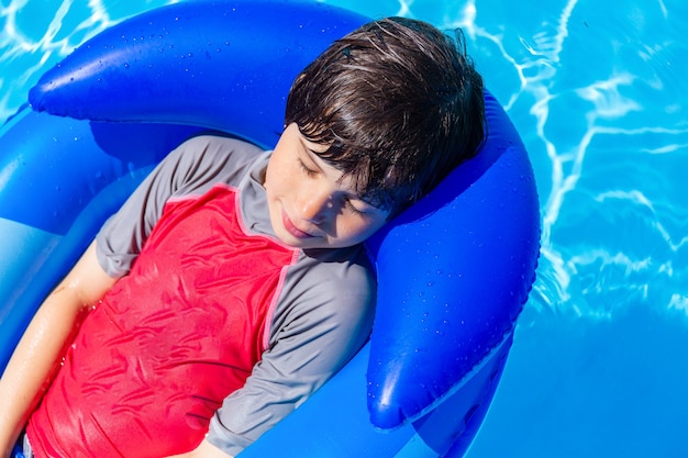 Adorable garçon se reposant dans la piscine sur un matelas gonflable