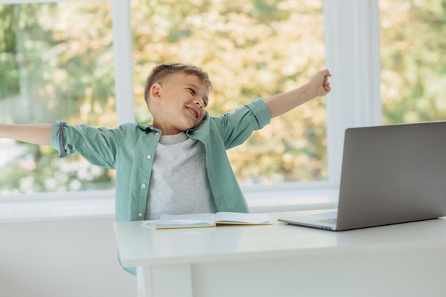 Adorable garçon souriant est heureux et utilise un ordinateur portable tout en faisant ses devoirs Place pour le texte