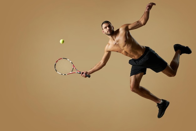 Photo adorable homme athlète portant des vêtements de sport jouant au tennis dans la chambre à l'intérieur