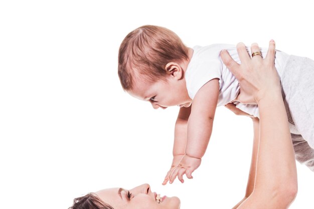 Adorable jeune mère tenant son bébé et le regardant sur fond blanc