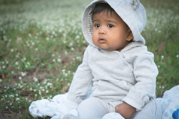 Adorable petit bébé asina assis au jardin de fleurs blanches