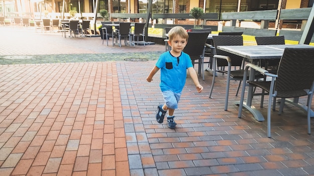 Adorable petit garçon de 3 ans courant sur une petite rue de la ville européenne