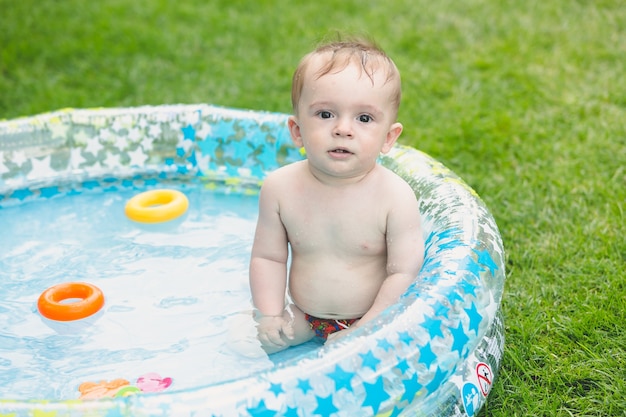 Adorable petit garçon de 9 mois assis dans la piscine gonflable