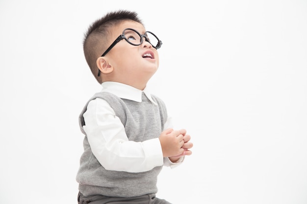 Adorable petit garçon asiatique vêtu d'une chemise blanche, gilet gris et lunettes isolées. Concept d'éducation des idées créatives et de l'innovation technologique