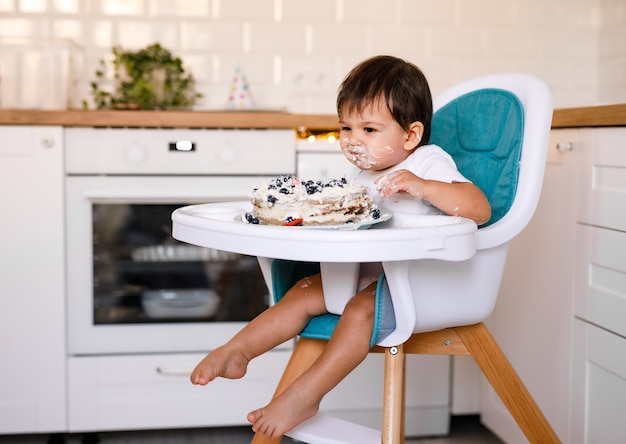 Adorable petit garçon célébrant son premier anniversaire et mangeant son premier gâteau. Fête d'anniversaire pour enfants décorée de ballons. Enfant mangeant un gâteau.