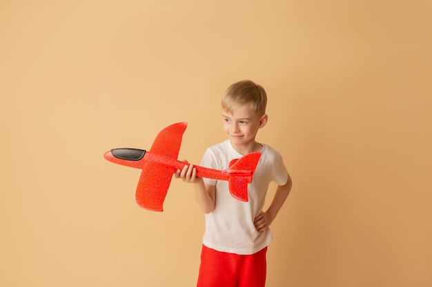 Adorable petit garçon jouant avec un avion rouge sur fond clair Concept d'enfants et de divertissement