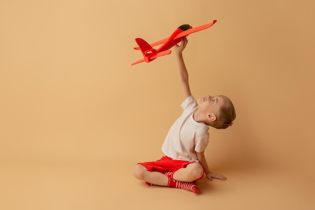 Adorable petit garçon jouant avec un avion rouge sur fond clair Concept d'enfants et de divertissement