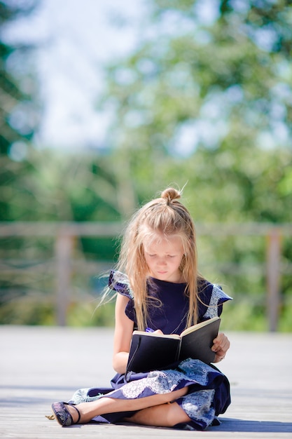 Adorable petite écolière avec des notes et des crayons en plein air. Retour à l'école.