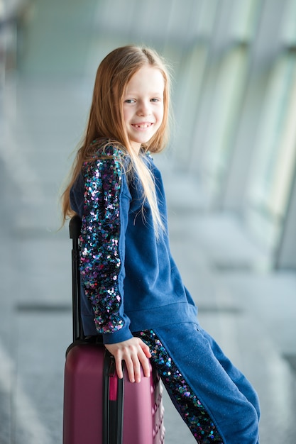 Adorable petite fille à l&#39;aéroport avec ses bagages en attente d&#39;embarquement