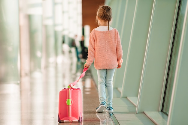 Adorable petite fille à l'aéroport avec ses bagages en attente d'embarquement