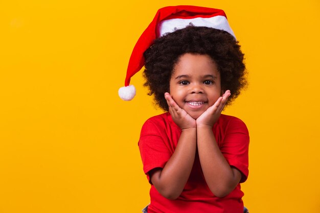 Adorable petite fille afro en t-shirt rouge et bonnet de Noel habillé pour noël avec un espace pour le texte