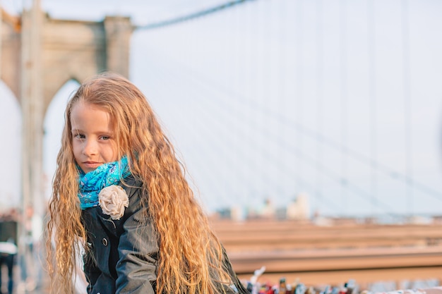 Adorable petite fille assise au pont de Brooklyn à New York