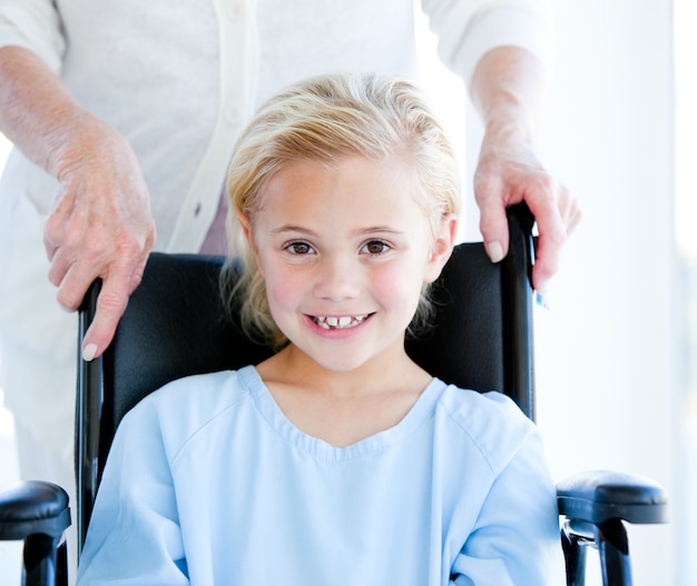 Adorable petite fille assise sur un fauteuil roulant