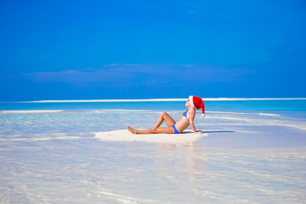 Adorable petite fille au bonnet de noel sur la plage pendant les vacances