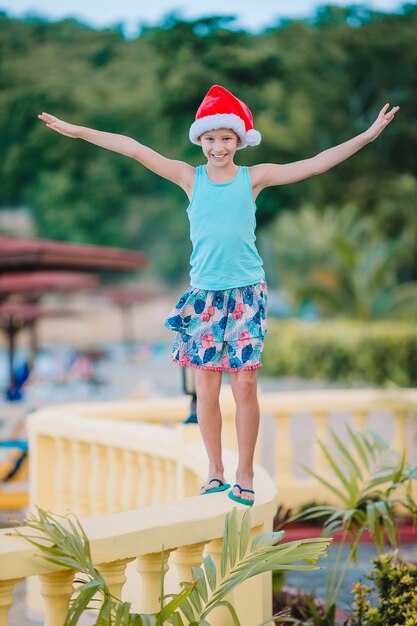 Adorable petite fille au bonnet de noel sur la plage tropicale