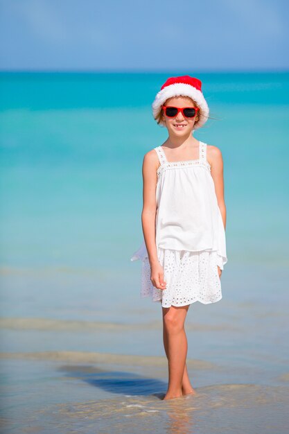 Adorable petite fille au bonnet de noel sur la plage tropicale