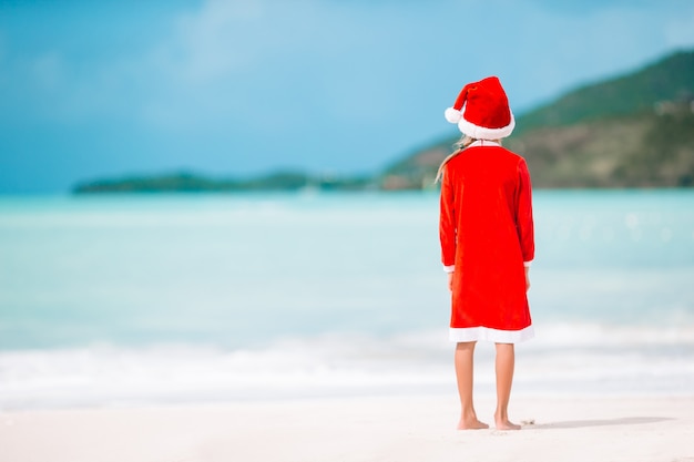 Adorable petite fille au bonnet de noel sur la plage tropicale