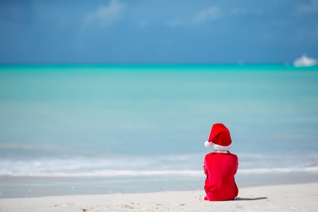 Adorable petite fille au bonnet de noel sur la plage tropicale